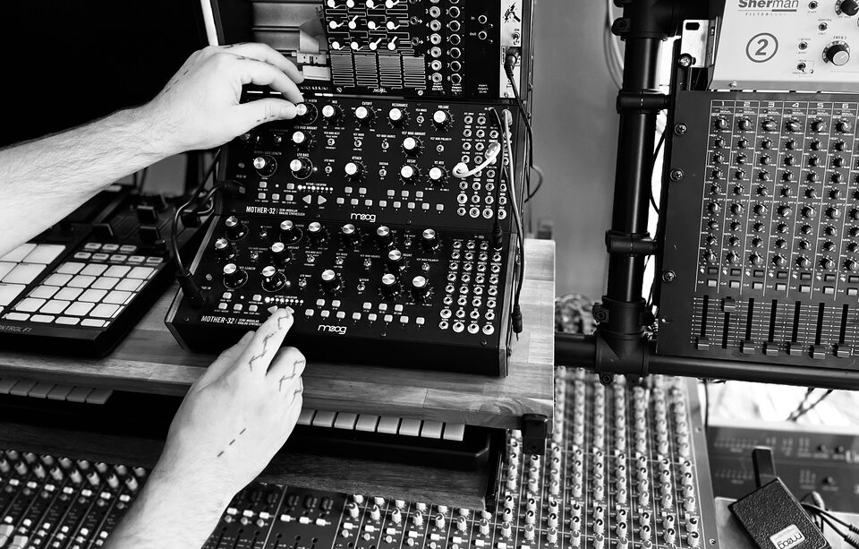 Hands adjusting synthesizer controls